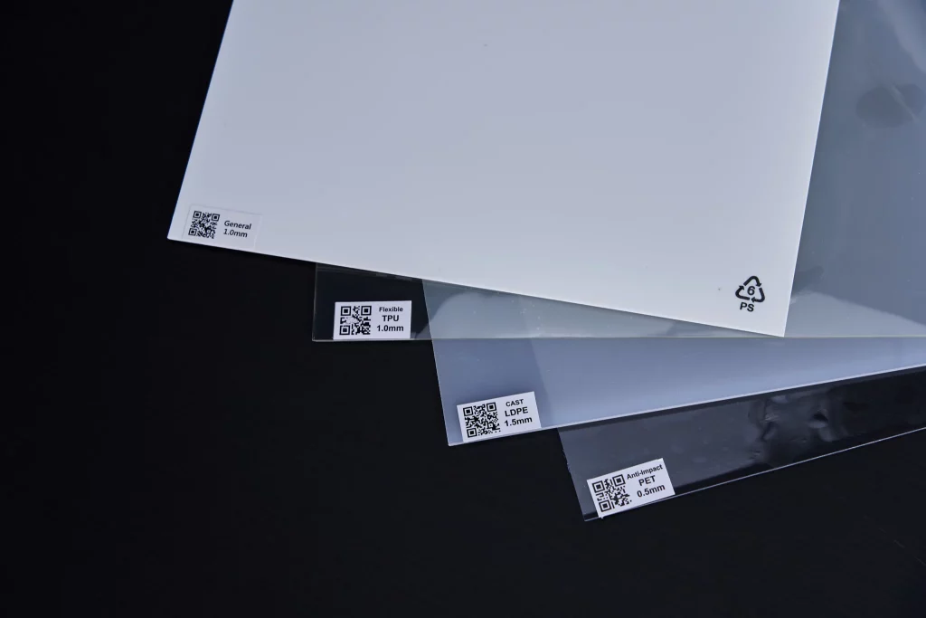 White HIPS plastic sheet, transparent TPU sheet & transparent PET sheet on black desk.