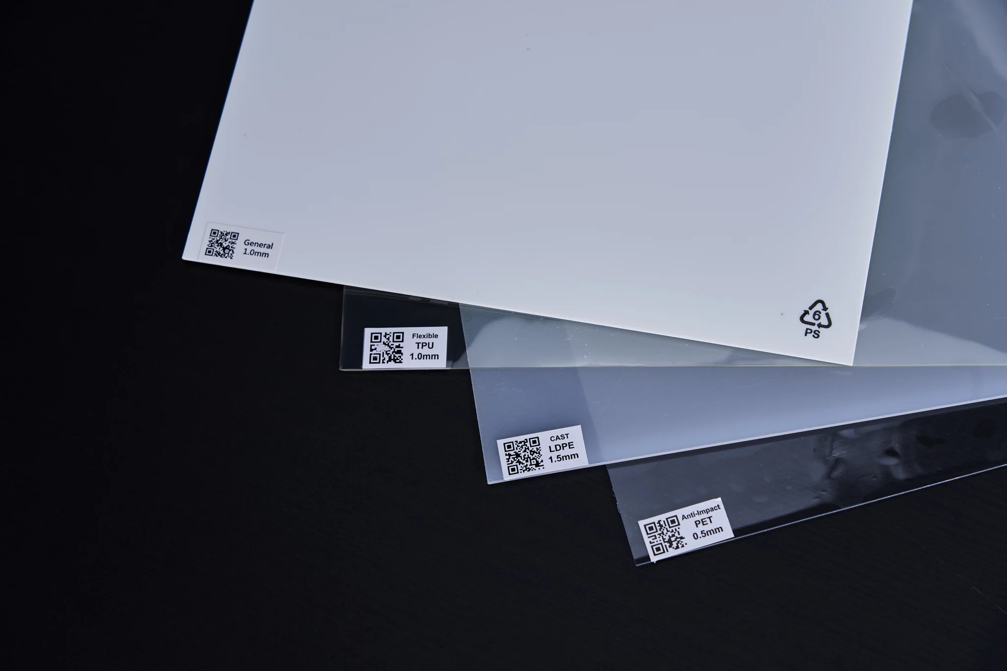White HIPS plastic sheet, transparent TPU sheet & transparent PET sheet on black desk.