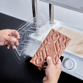 Two hands are holding the newly molded PET chocolate mold and demonstating the finished chocolate.