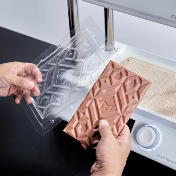 PET sheet for vacuum forming Two hands are holding the newly molded PET chocolate mold and demonstating the finished chocolate.