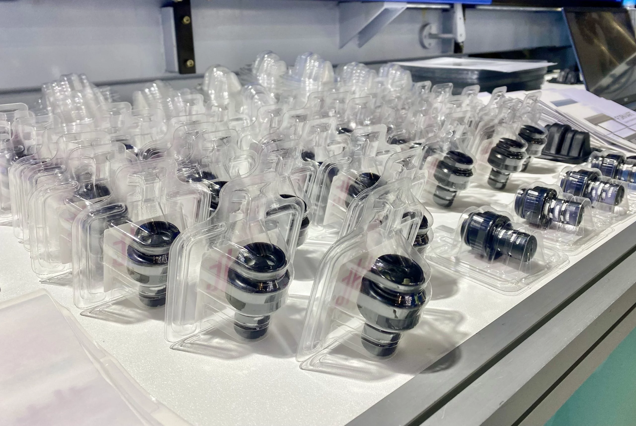 Many water filter spouts for bottled water, packaged in vacuum-formed clamshells, placed on a table.
