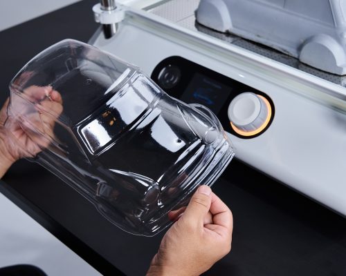 A newly formed transparent RC car body being held in hand