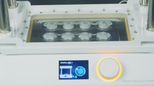 The Smart Vacuum Former is in operation, displaying the mold-making process on the screen, with multiple molded chocolate pieces inside the machine