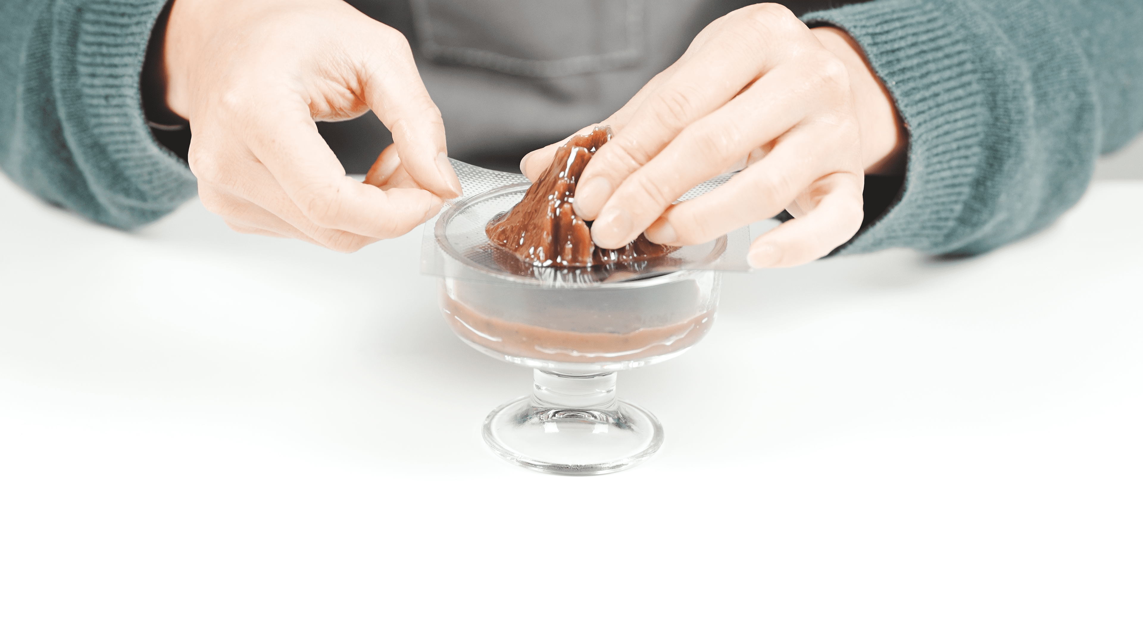 手で火山型の羊羹型をガラスカップに慎重に置き、次の工程の準備をしている。