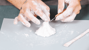 Hands carving a volcano shape out of clay with a tool, preparing to make a yokan mold.