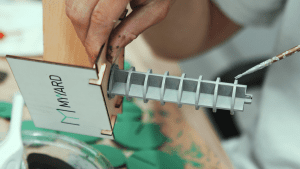 The designer is painting the MYYARD model sign, showcasing the detailed design and manual painting process.