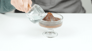Hands pouring liquid into the volcano-shaped yokan mold, preparing to complete the dessert.