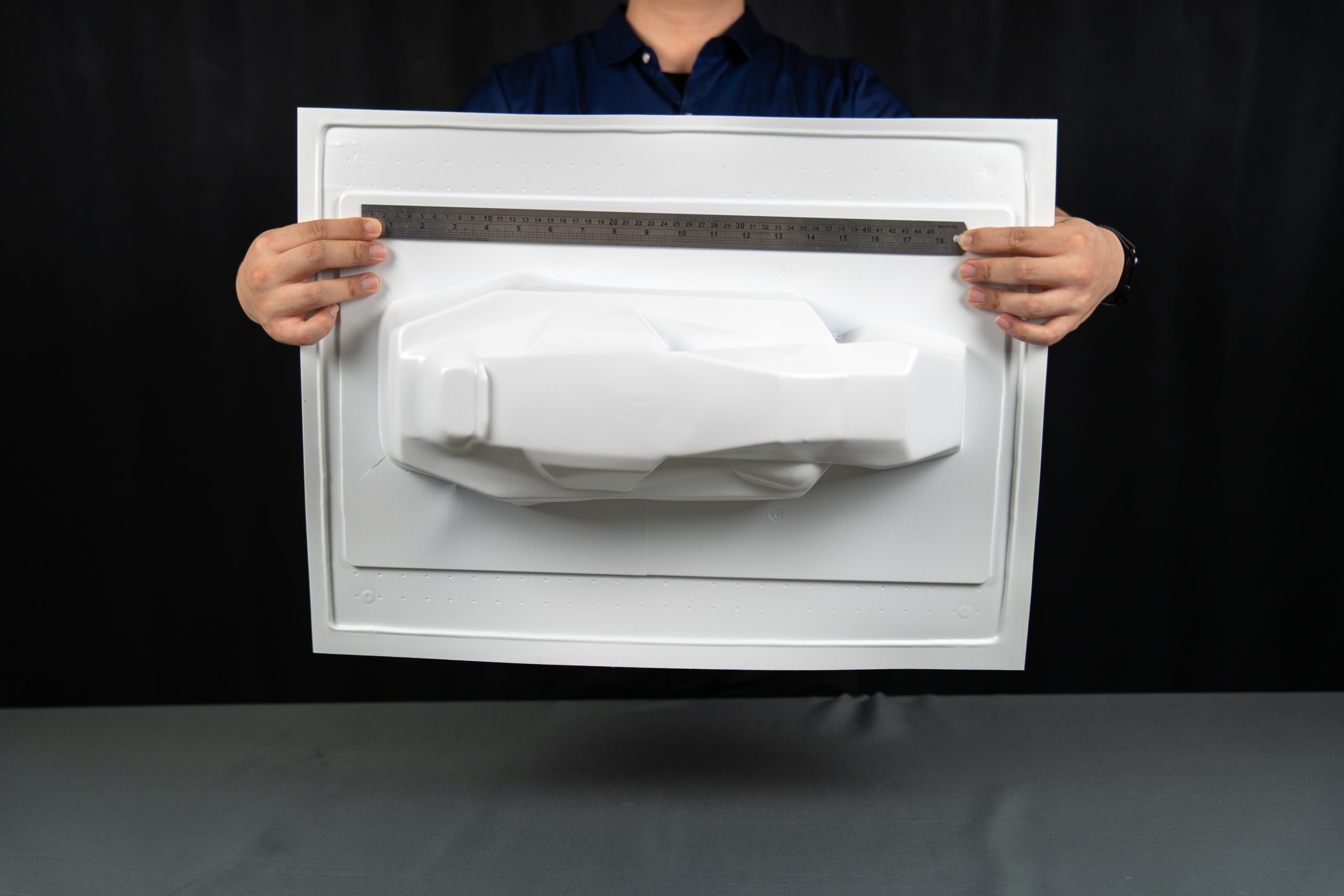 FORMOVA DM-09 A person holds a white vacuum-formed plastic sheet with a car-shaped form, using a ruler to show its width.
