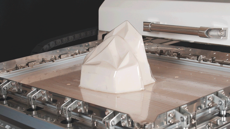formova-demo-02 A clear plastic sheet takes shape over a geometric mold inside a vacuum former.